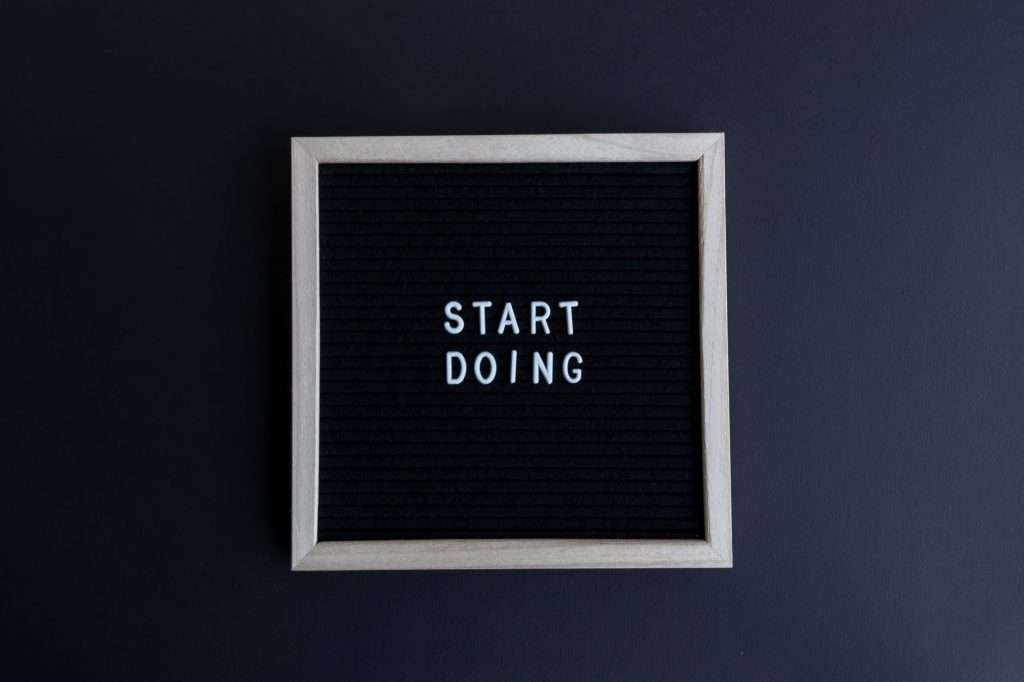 Black letter board with the motivational phrase 'Start Doing' in white text on a gray background.