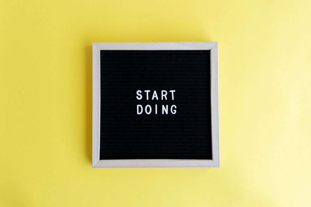 Black message board with 'Start Doing' on a bright yellow background for inspiration.