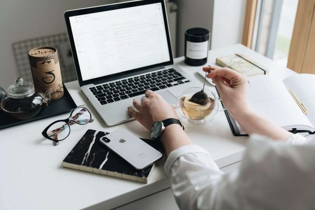 A cozy home office scene with a laptop, tea, and workspace essentials.