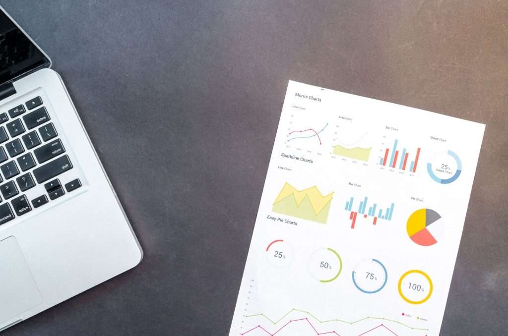Modern desk setup with a laptop and analytical charts showcasing data interpretation and business analysis.