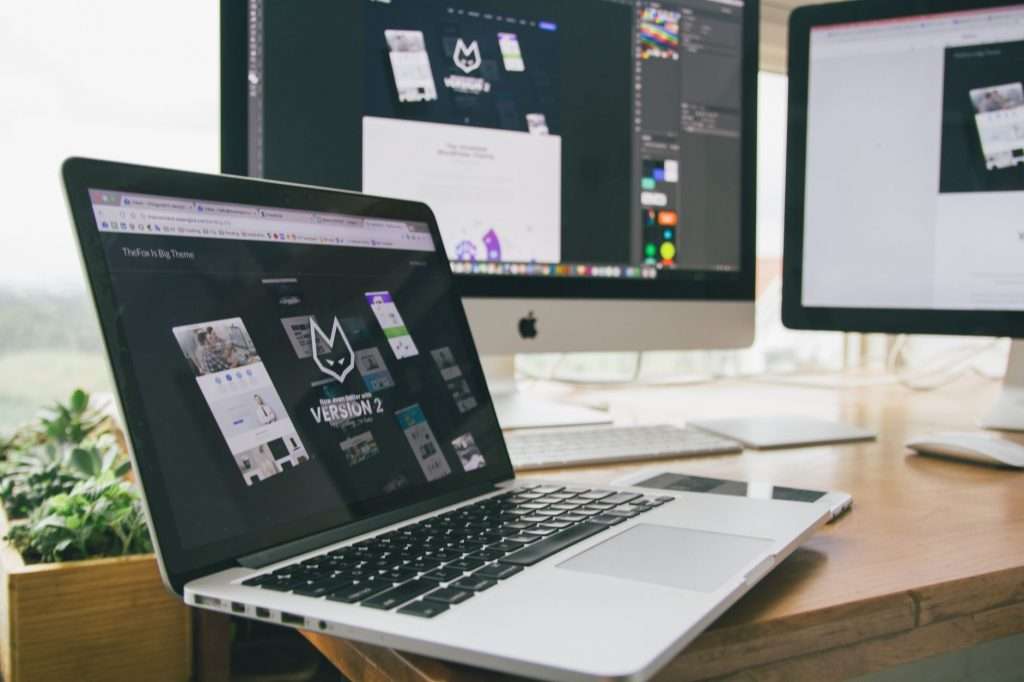 A stylish workspace featuring a laptop and monitors displaying design software.