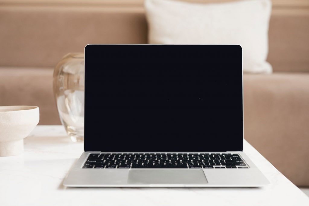 A modern laptop with a blank screen on a table in a cozy indoor environment, perfect for mockup use.