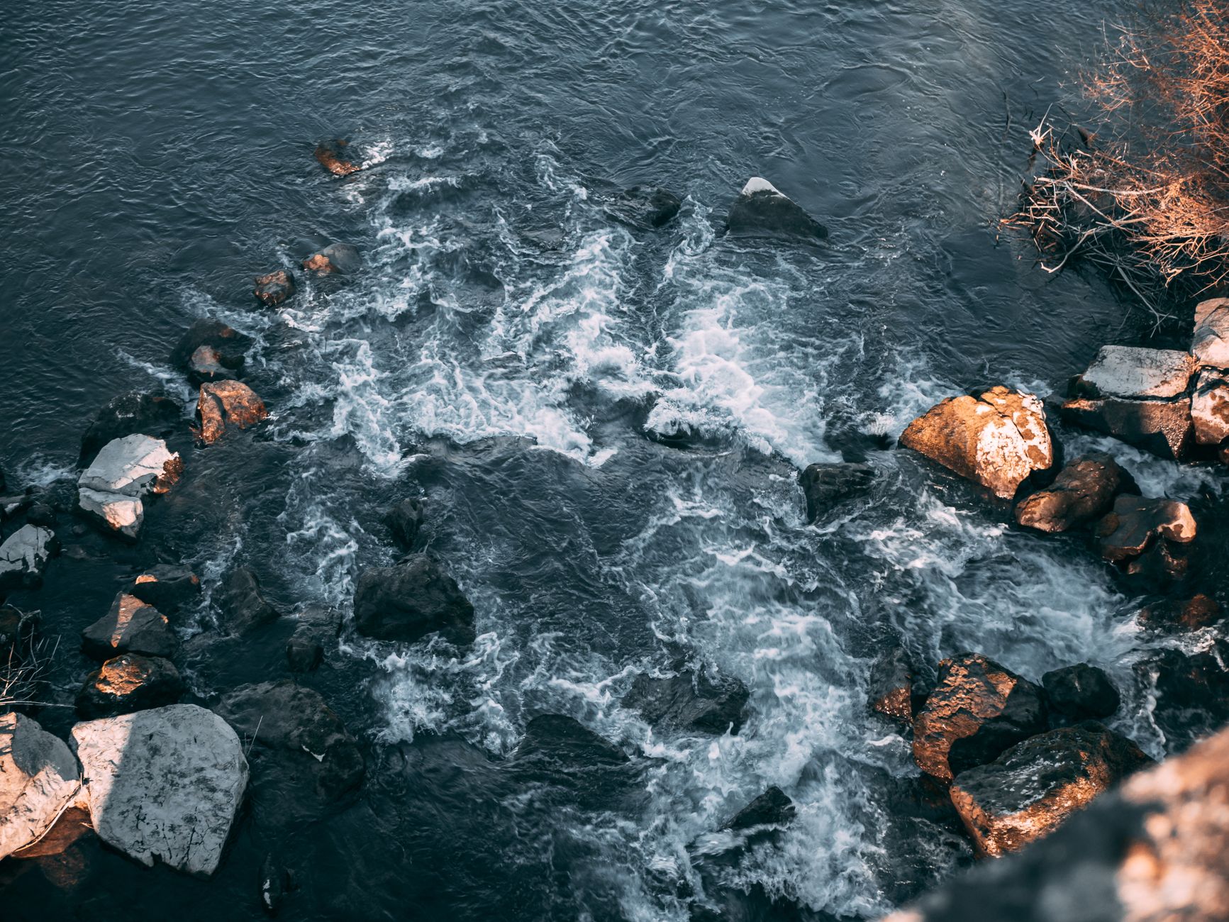 A stunning view of river rapids flowing over rocks with surrounding vegetation.