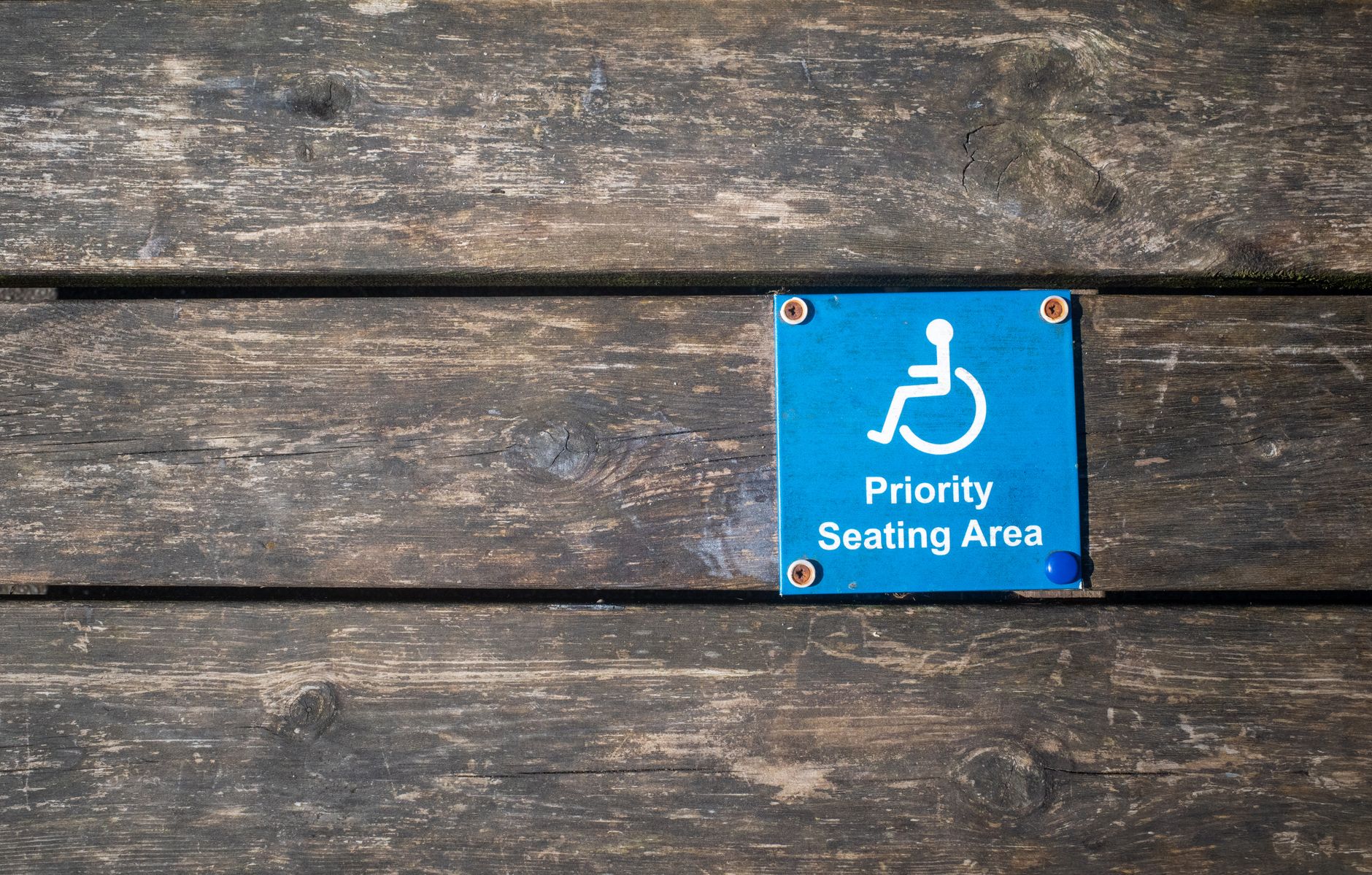 Close-up of a priority seating area sign with wheelchair symbol on a wooden surface.