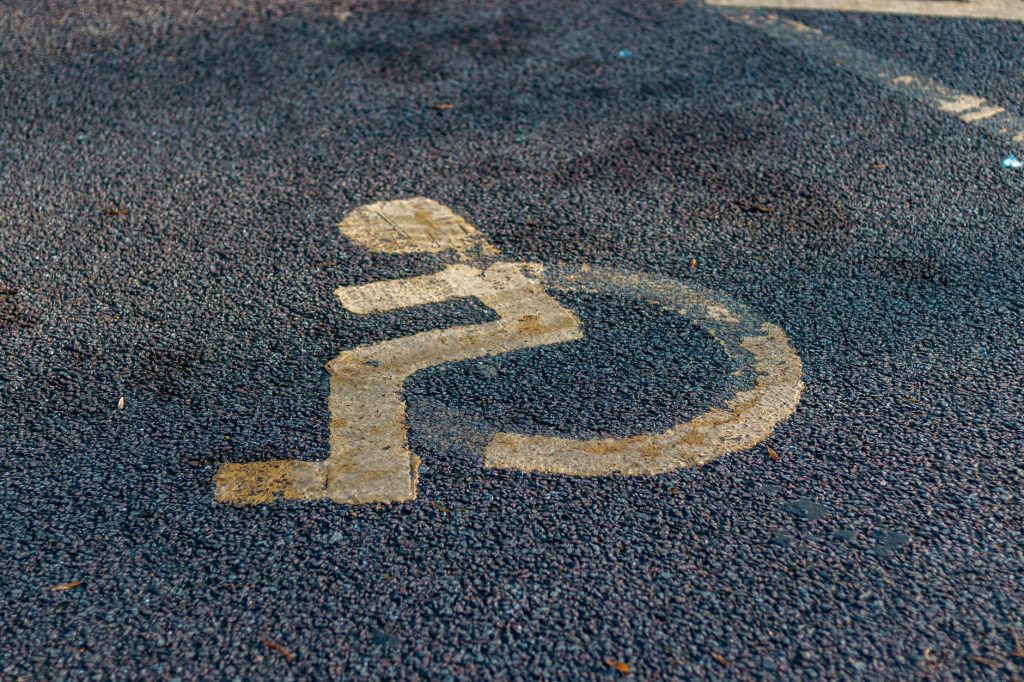 Close-up of a weathered handicap sign painted on a pavement, emphasizing accessibility.