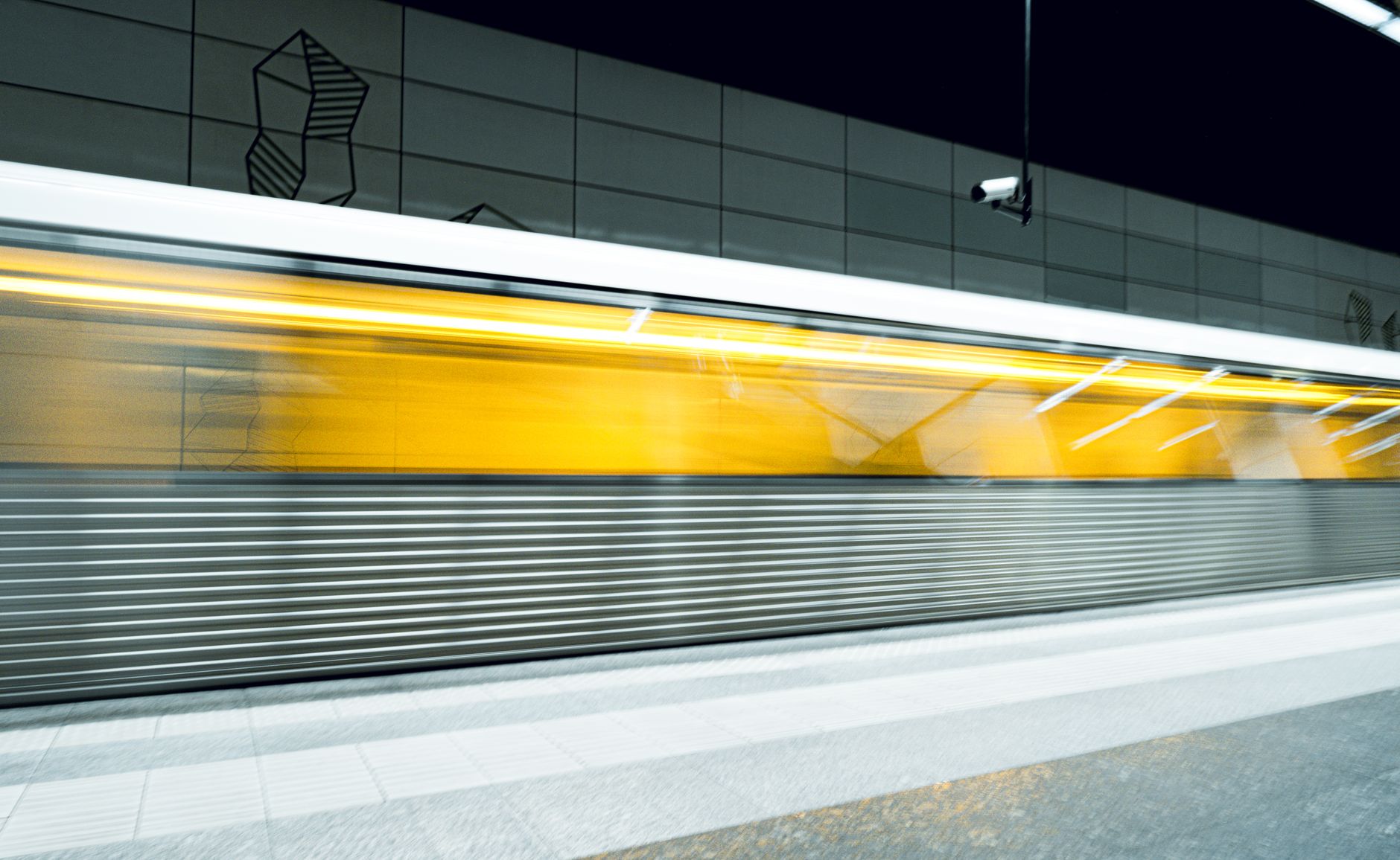 Dynamic shot of a yellow subway train in motion at a modern metro station.