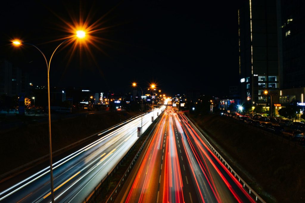 Long exposure photo capturing light trails on a busy highway at night with city lights.