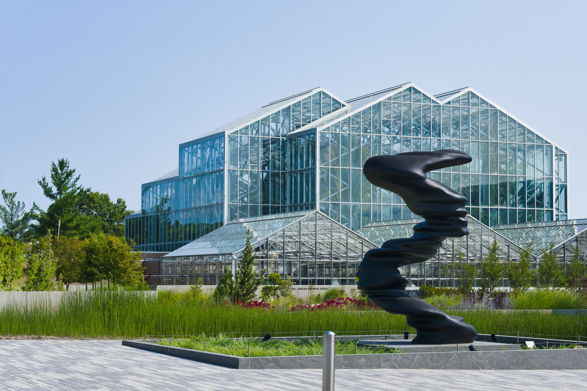 Modern architectural greenhouse in Grand Rapids, MI park with sculpture.