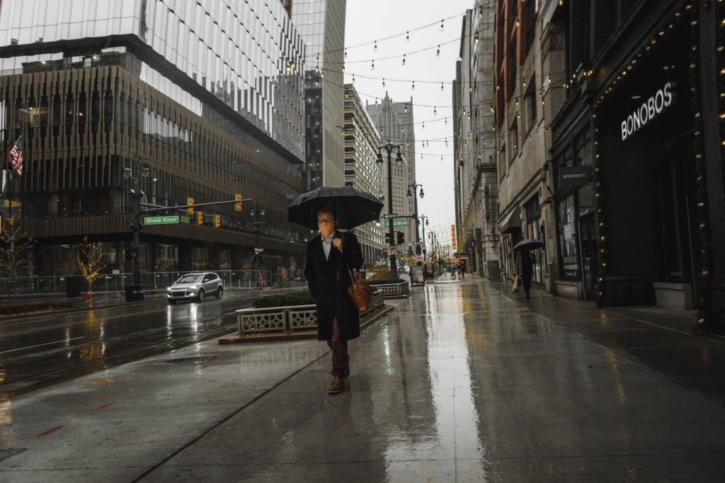 Person walking with an umbrella on a rainy day in downtown Detroit, showcasing urban life.