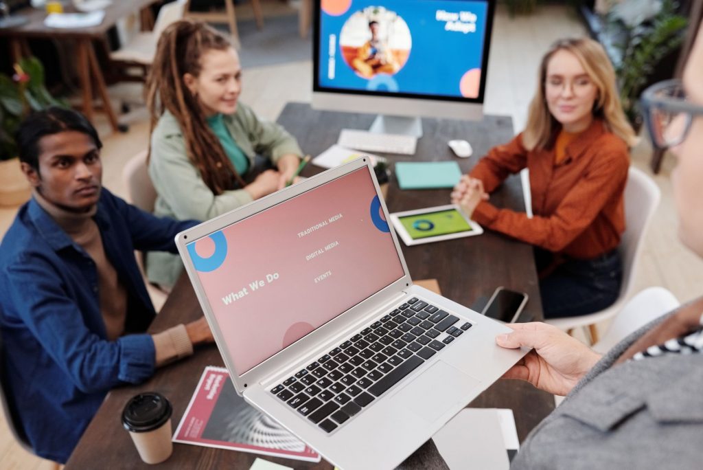 Team collaboration in an office setting with a laptop presentation and diverse colleagues.