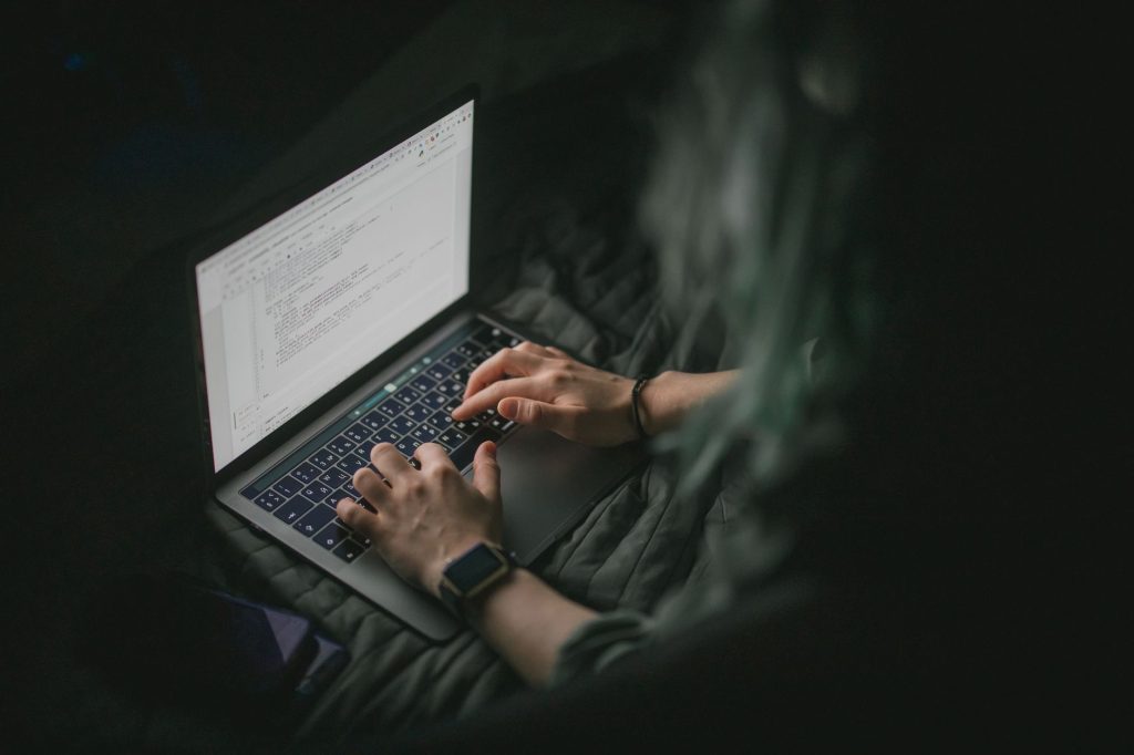 Close-up of hands typing on a laptop with code on screen, perfect for work from home and tech themes.