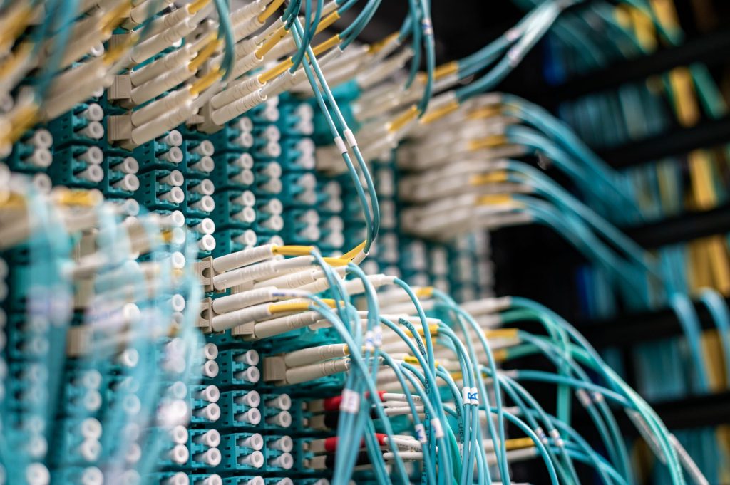 From below of long thin blue cables connected to row of small white connectors on system block in data center